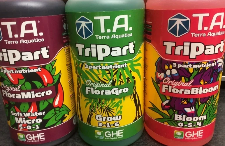 Three bottles of Terra Aquatica cannabis nutrients showing the N-P-K ratios for FloraMicro, FloraGro, and FloraBloom to illustrate the difference between vegetative and flowering plant food.